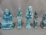 five ancient egyptian figurines sitting in a row on a table