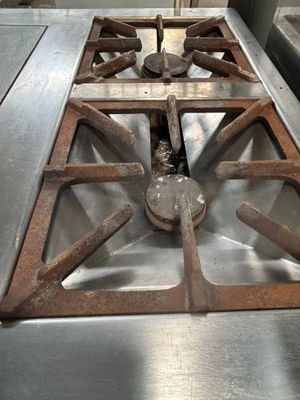 une plaque de cuisson en métal sur laquelle est posé un brûleur en métal