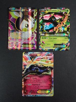 trois cartes Pokémon différentes posées sur une table avec un fond noir