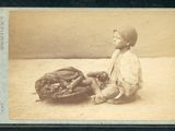 une vieille photo d'un jeune garçon assis par terre avec un gant de baseball