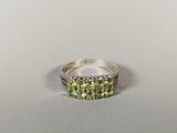 a close up of a silver ring with green stones on it