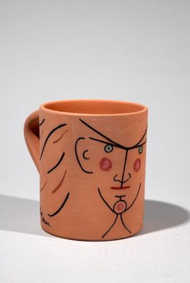 un gobelet orange sur lequel est dessiné le visage d'une femme