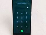 the back of a black phone with a green button on the screen