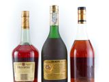 three bottles of alcohol are lined up on a white surface