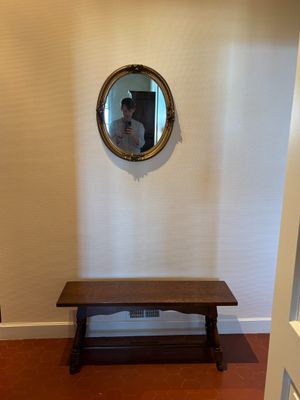a wooden bench in a room with a mirror on the wall