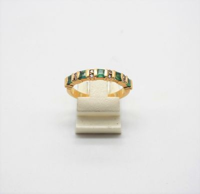 a close up of a gold ring with green stones on it