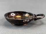 une petite tasse en argent avec une anse, posée sur une table