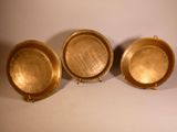 three gold plates sitting next to each other on a white surface