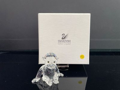 figurine en cristal représentant un ours en peluche assis devant une boîte blanche