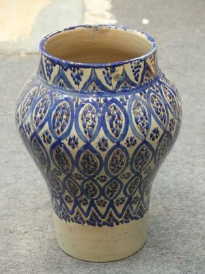 a blue and white vase sitting on the ground