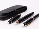 three pens and a case on a white surface