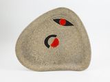 a stone with a face on it sitting on a white surface