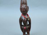 une vieille figurine en bois représentant un homme avec un ruban rouge autour du cou