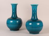 une paire de vases bleus posés l'un à côté de l'autre sur une surface blanche