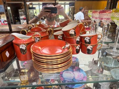 a man taking a picture of a display of cups and saucers