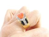 a woman ' s hand holding a ring with an orange stone on it