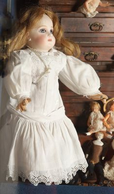 a doll that is standing in front of a chest of drawers