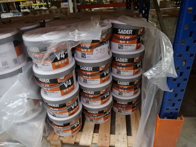 Plusieurs seaux de peinture sont empilés sur des palettes dans un entrepôt