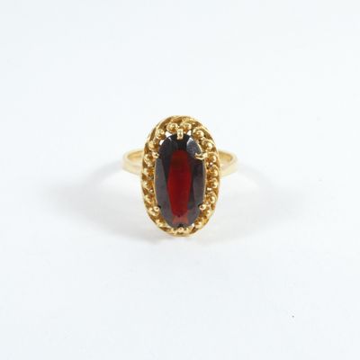 gros plan d'une bague en or avec une pierre rouge