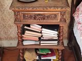 a wooden table with books on it next to a bed