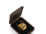 a gold ring in a black box on a white surface