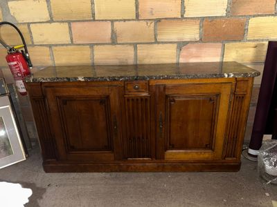 une armoire en bois avec un plateau en marbre, à côté d'une borne d'incendie