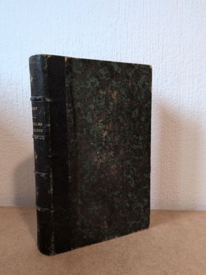 un vieux livre noir posé sur une table près d'un mur blanc