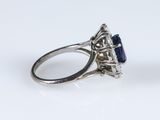 a close up of a diamond and sapphire ring on a white surface