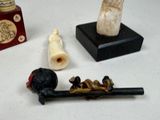 a small collection of items that include a pipe, a pipe holder, and a figurine