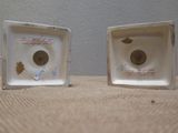 two small white vases that are sitting on a table