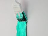 a paint brush with green paint on it on a white wall