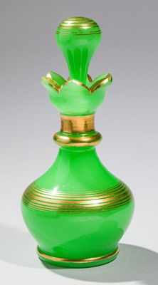 vase en verre vert orné d'une bordure dorée, posé sur une surface blanche