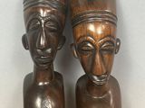une paire de sculptures africaines représentant des têtes, posées sur une étagère en bois