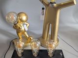 a gold statue of a man and a light bulb on a table