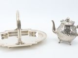 two silver teapots and a tray on a white surface
