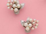 une paire de broches en forme de fleurs, en perles et en argent, sur fond rose