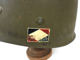 an old military helmet with a sticker on it sitting on a wooden stand