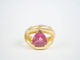 a close up of a pink sapphire ring on a white surface