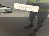 a man standing in front of a car holding a sign