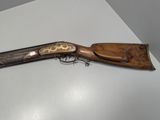 an old rifle with a wooden handle on a white table