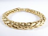 gros plan d'un bracelet en or sur une surface blanche