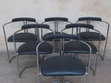 six black leather chairs in a row against a white wall