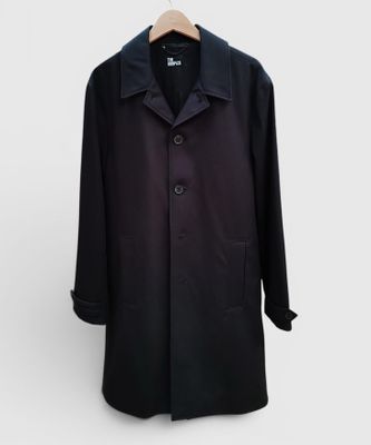 un manteau noir suspendu à un cintre sur un mur blanc