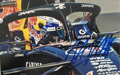 photo dédicacée d'une voiture de course avec un casque sur la tête du pilote