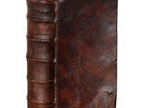 an old leather book sitting on top of a white surface