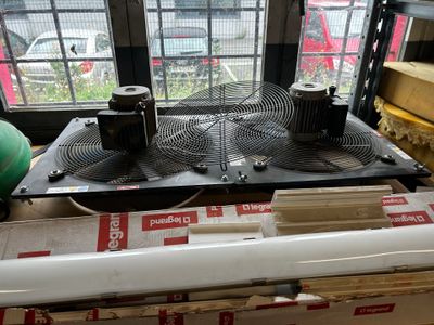 two air conditioners sitting on top of a box in front of a window