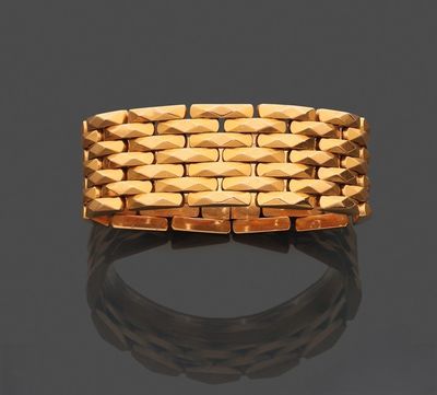 gros plan d'un bracelet en or sur une surface noire