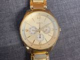 a gold watch with a white face on a gray surface
