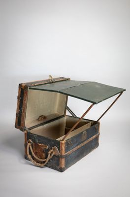 une vieille valise avec un couvercle en verre, posée sur une surface blanche