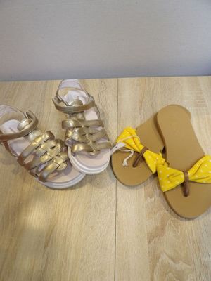 pair of gold and white sandals with a yellow bow tied to them